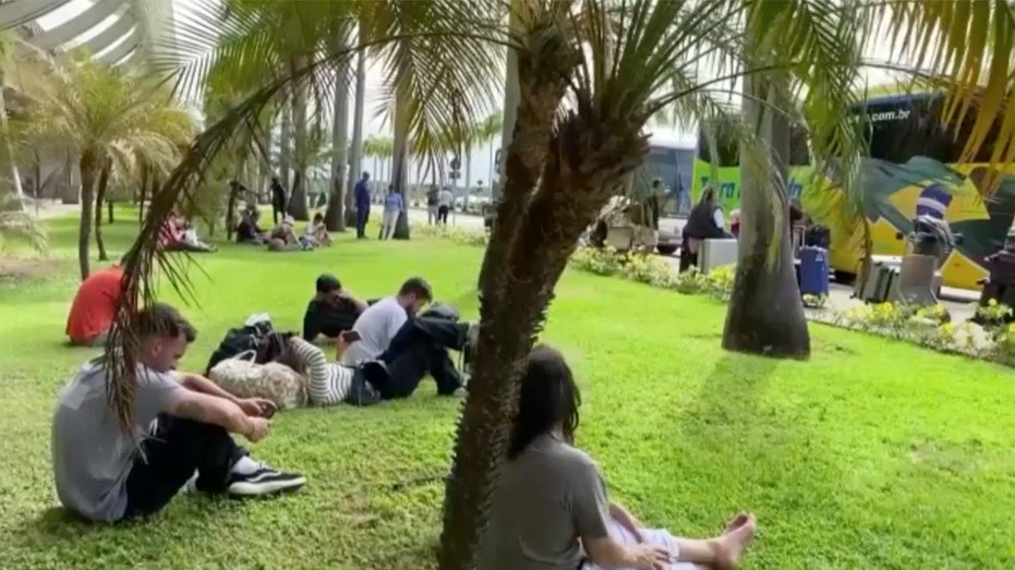 Air Europa passengers wait in grass