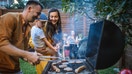 A family hosts a barbecue in the backyard of their home.